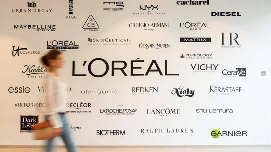 woman walking past a wall with cosmetic brands logo