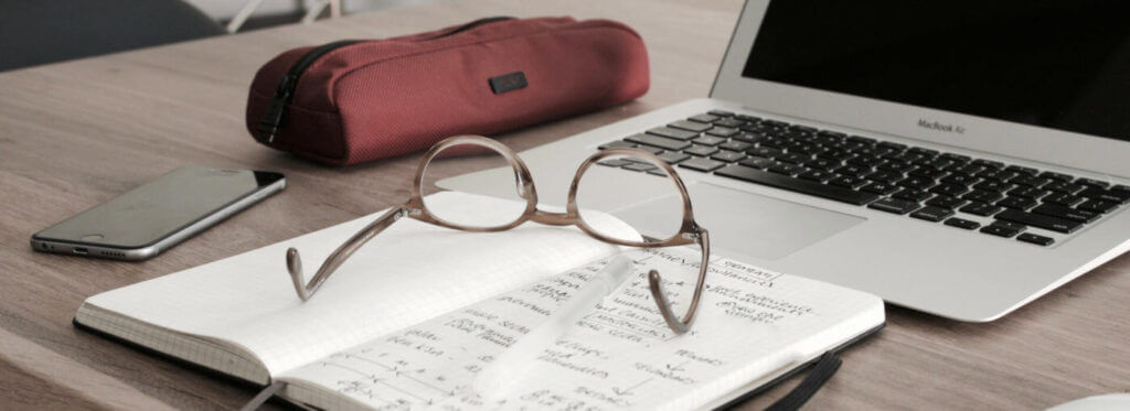 glasses on a notebook in front of a laptop