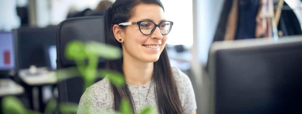 woman with glasses smiling while working
