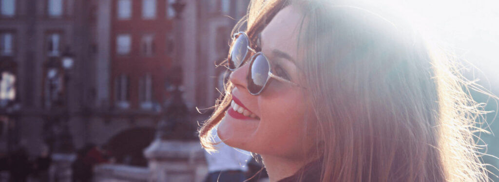 happy young woman with sunglasses smiling in the sun