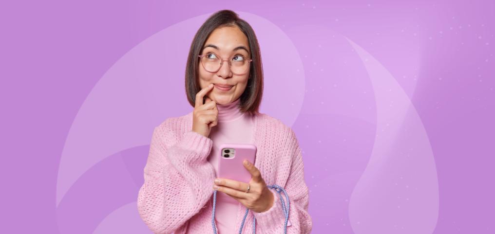 girl dressed in pink, holding a pink smartphone with an intrigued facial expression
