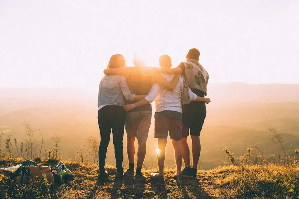 group of people hugged looking at the sunset
