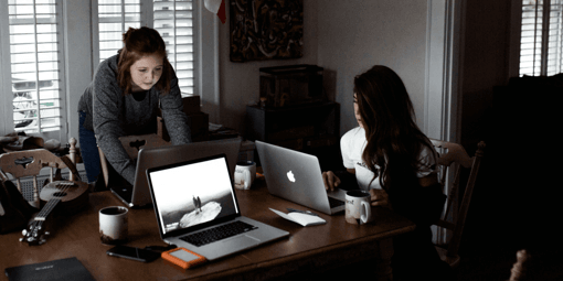 two women working on laptops in an office