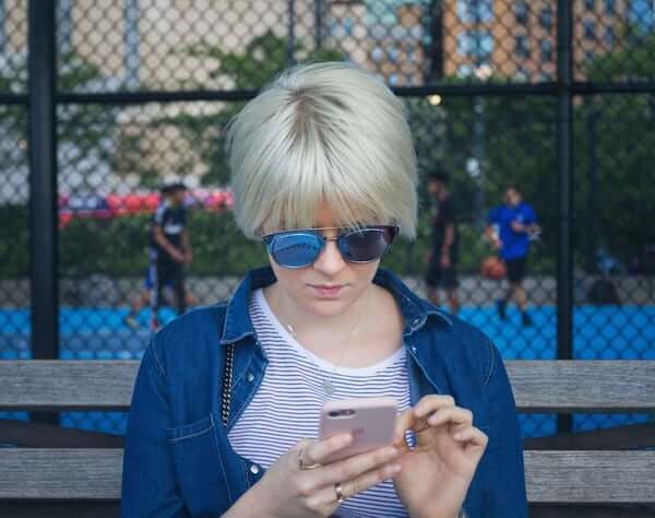 woman with sunglasses typing on phone