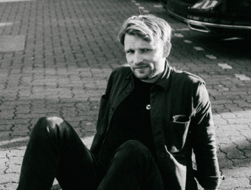 a black and white photo of a man sitting on the street