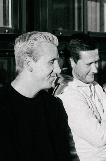 a black and white photo of two men talking
