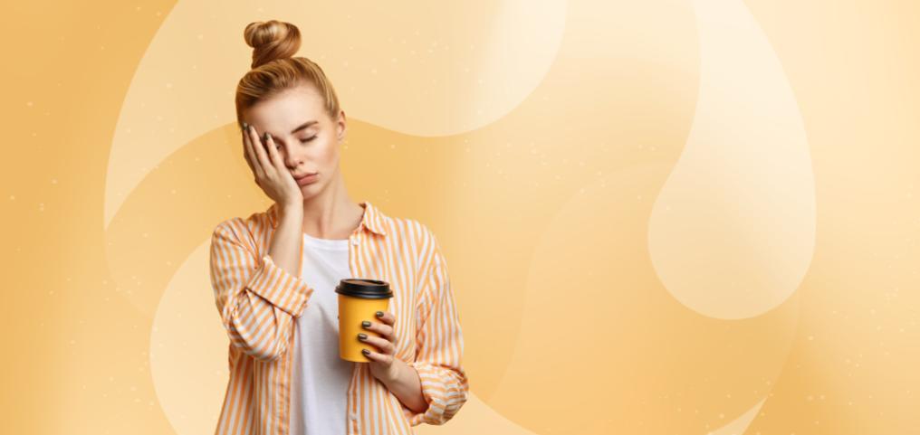 woman standing, feeling sleepy, holding a cup of coffee in hand